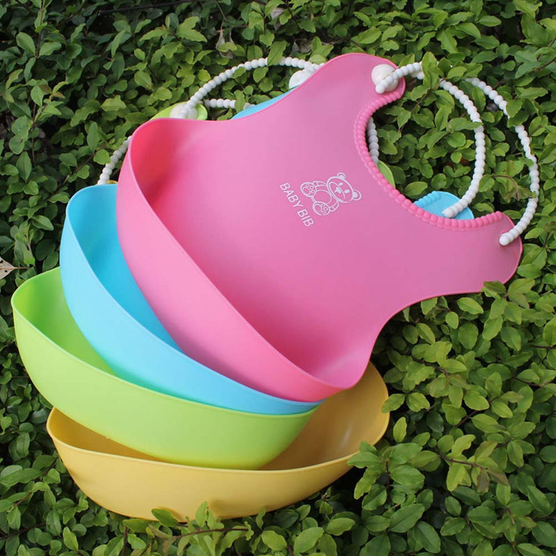 Layered view of silicone baby bibs by Baby Bliss Haven, featuring pink, blue, green, and yellow bibs all designed with fun graphics for infants.