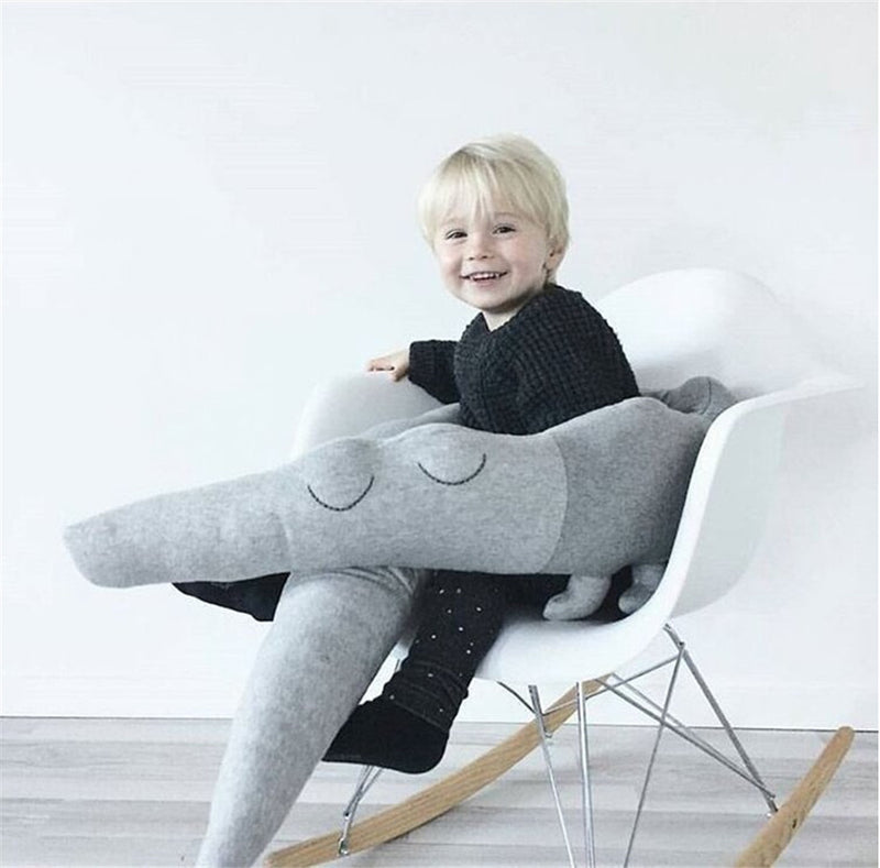 A joyful child seated on a chair with gray cartoon baby bedding wrapped around, illustrating the multifunctional use of Baby Bliss Haven's playful designs.